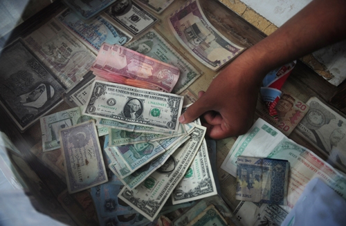 A Pakistani money exchange dealer displays foreign currency notes at his roadside stall in Karachi on August 24, 2012. The Pakistani rupee sank to an all-time low against the dollar Friday on high oil prices and forex reserve fears as the country prepared to repay nearly $400 million to the International Monetary Fund.   AFP PHOTO/ Asif HASSAN        (Photo credit should read ASIF HASSAN/AFP/GettyImages)